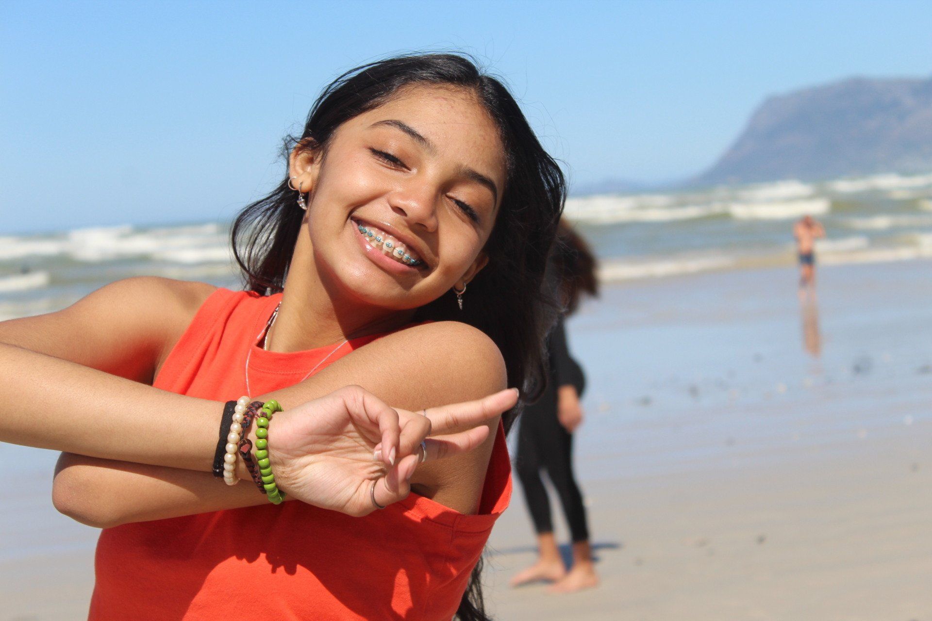 a young girl with braces on her teeth is standing on a beach .