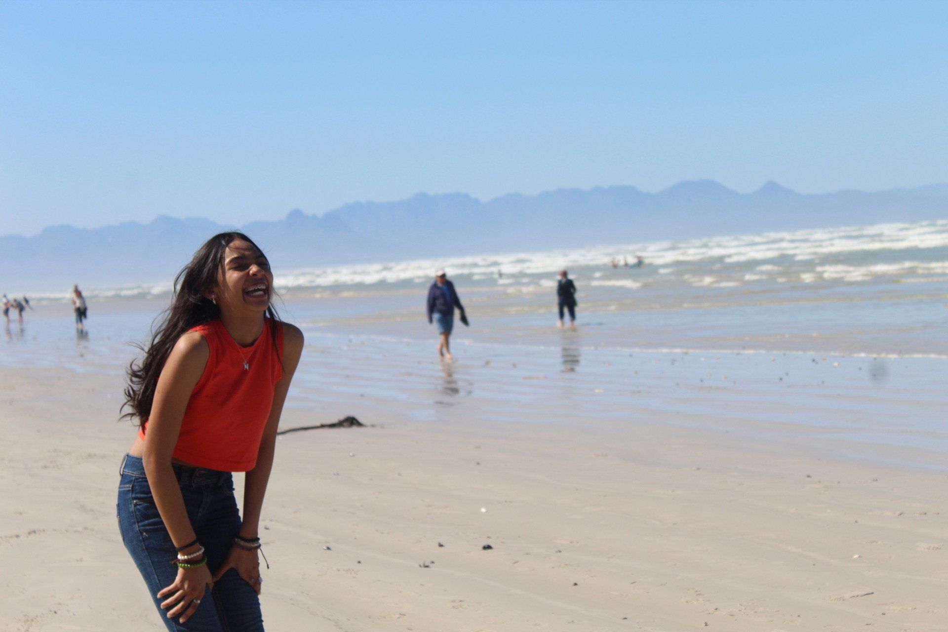a woman is standing on a beach with her hands on her knees .