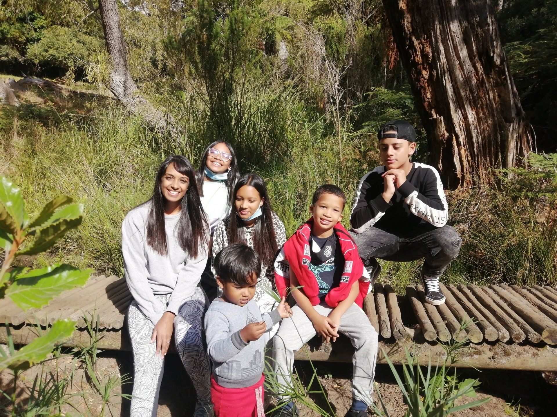 a group of people are sitting on a wooden bridge .