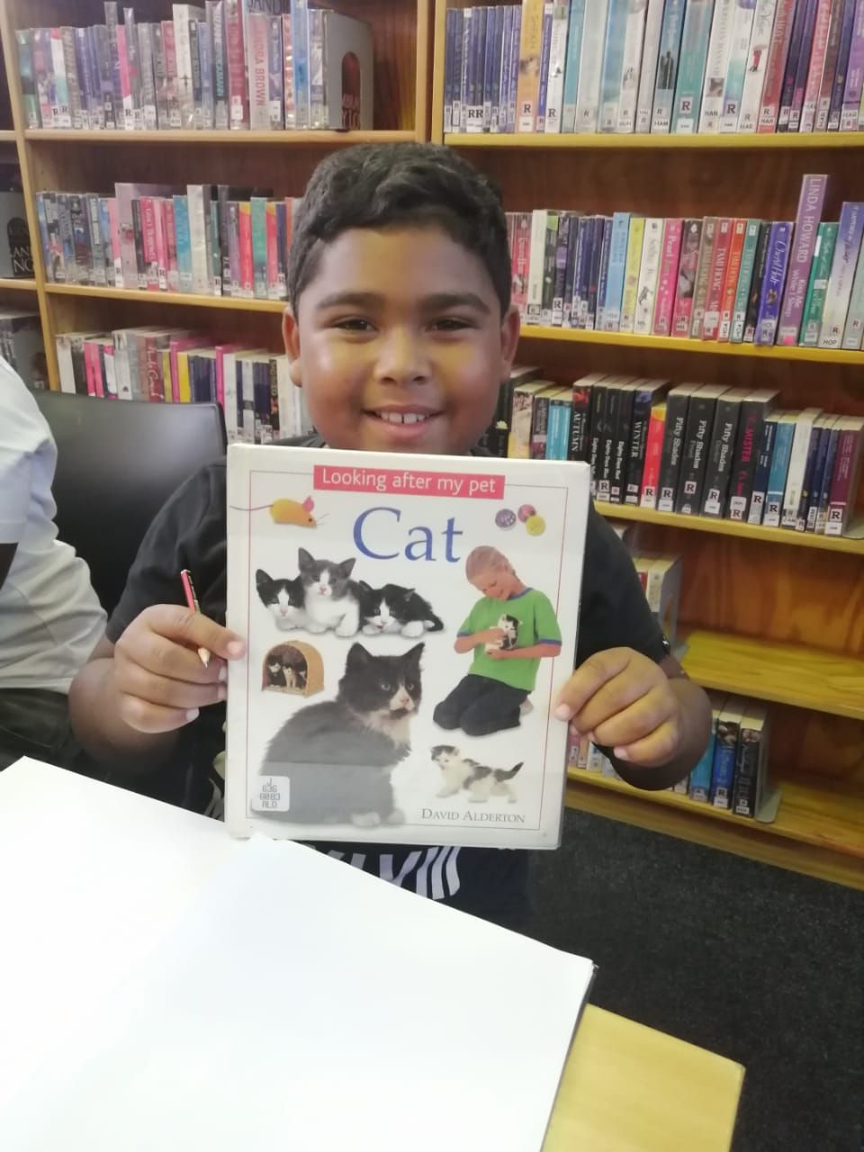 a young boy is holding a book titled cat