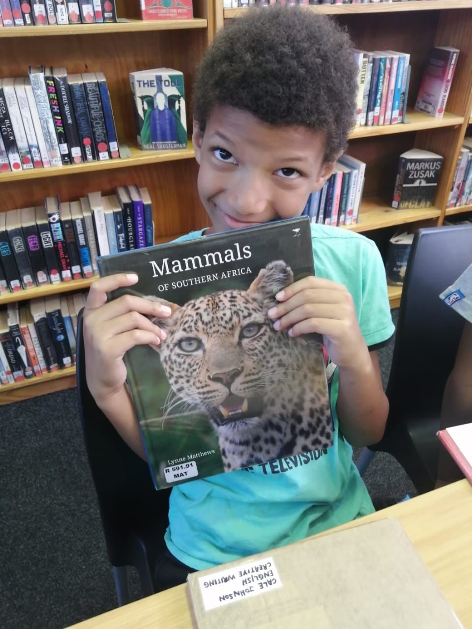 a young boy is holding a book about mammals