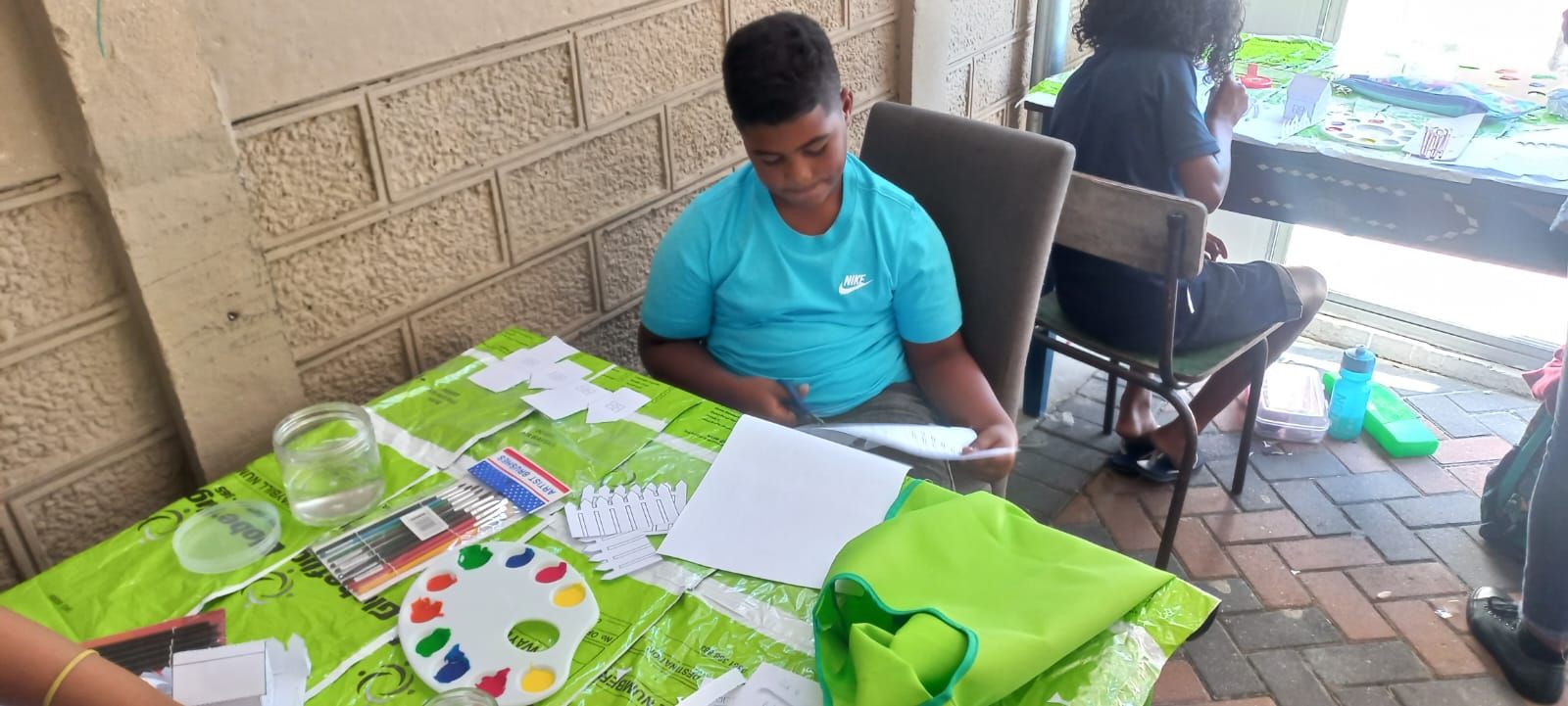 a boy is sitting at a table with a green table cloth .