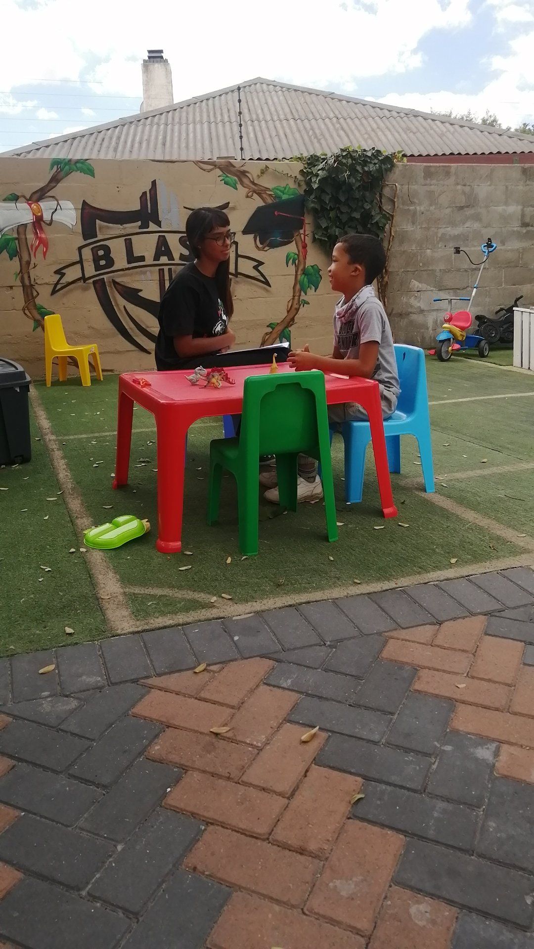 two children are sitting at a table in a playground .