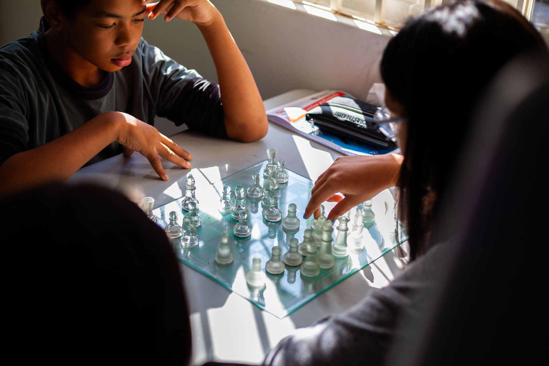 a boy and a girl are playing a game of chess .
