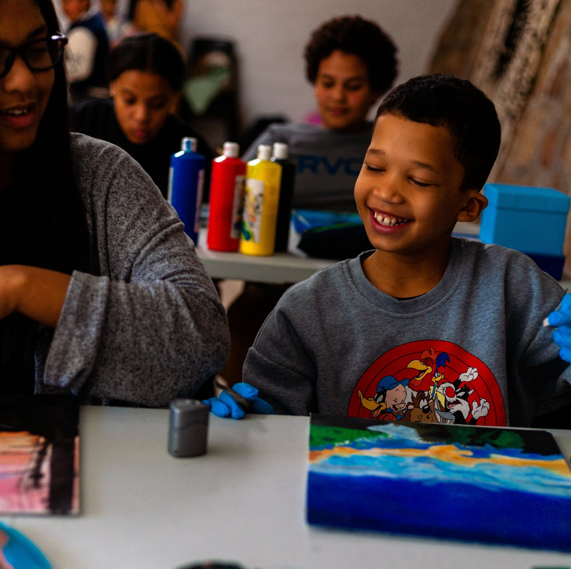 a boy wearing a rvc shirt is painting a picture
