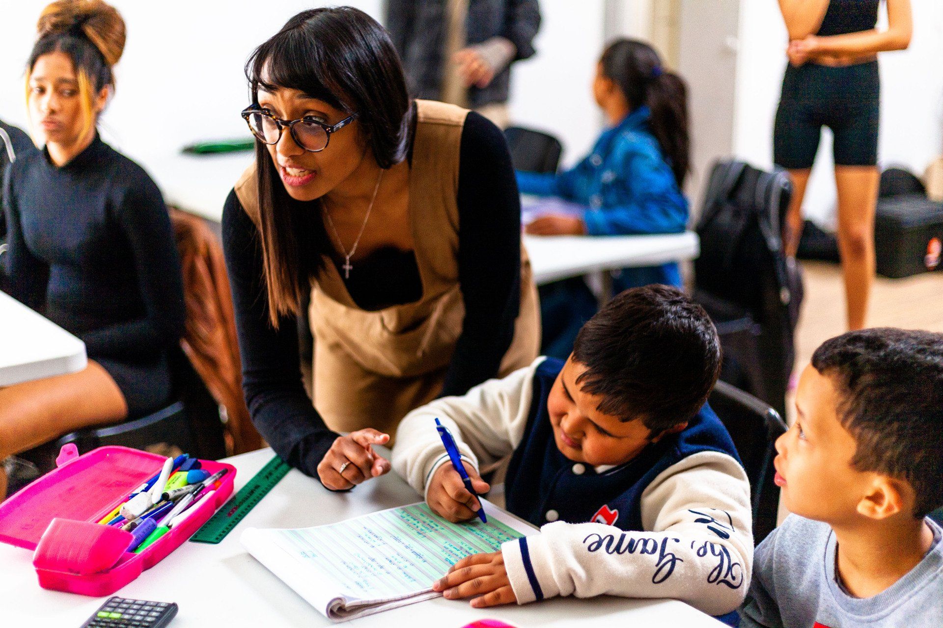 a woman is helping a boy with his homework in a classroom .