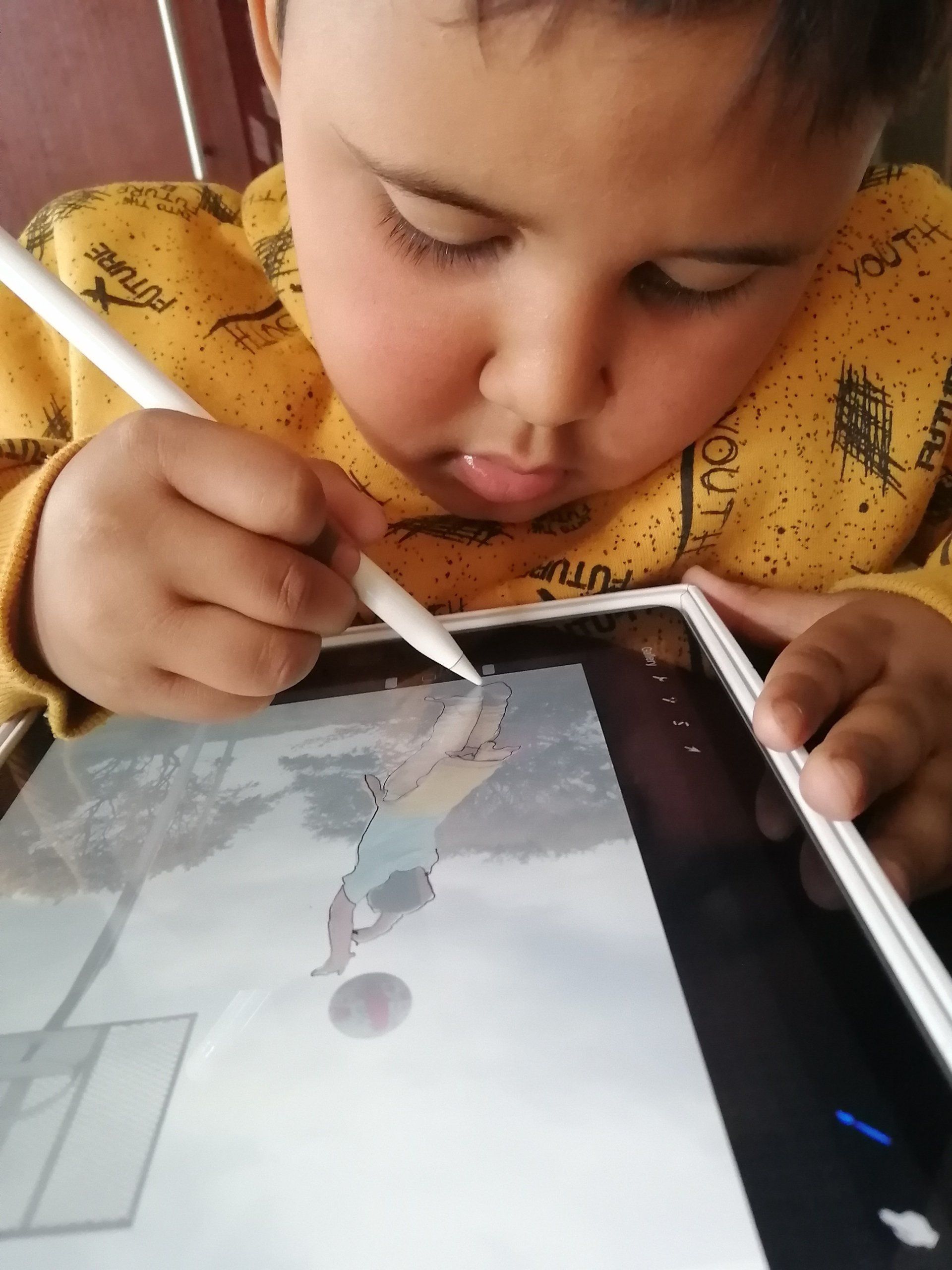 a young boy is drawing on a tablet with a pen