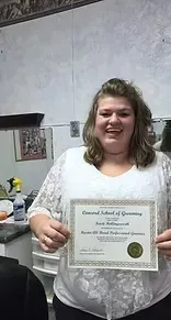 Woman holding a certificate, smiling. She's in a white shirt with a white lace overlay.