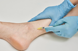 Person's ankle receiving injection by gloved hands holding a syringe.