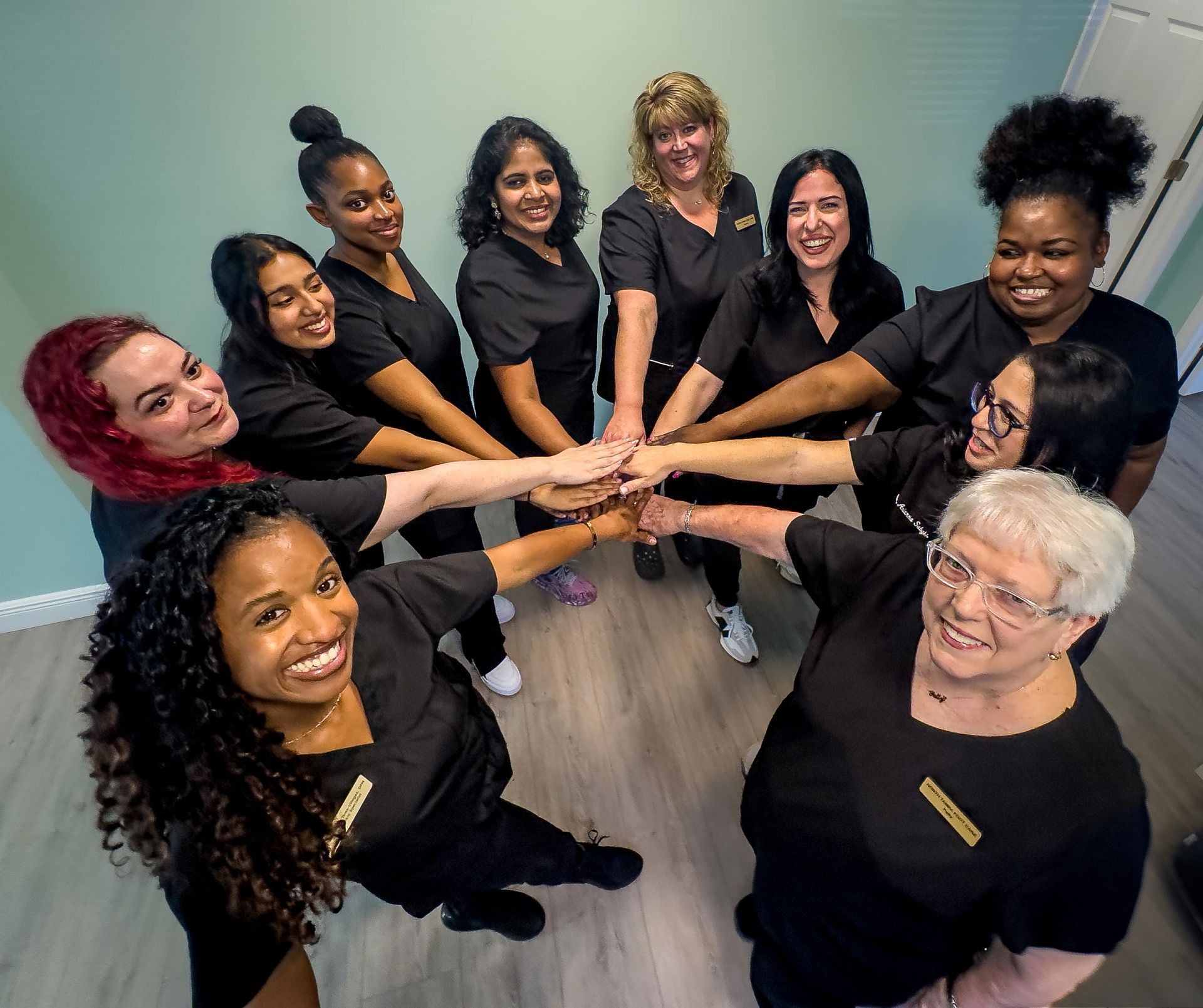 A group of women are putting their hands together in a circle.