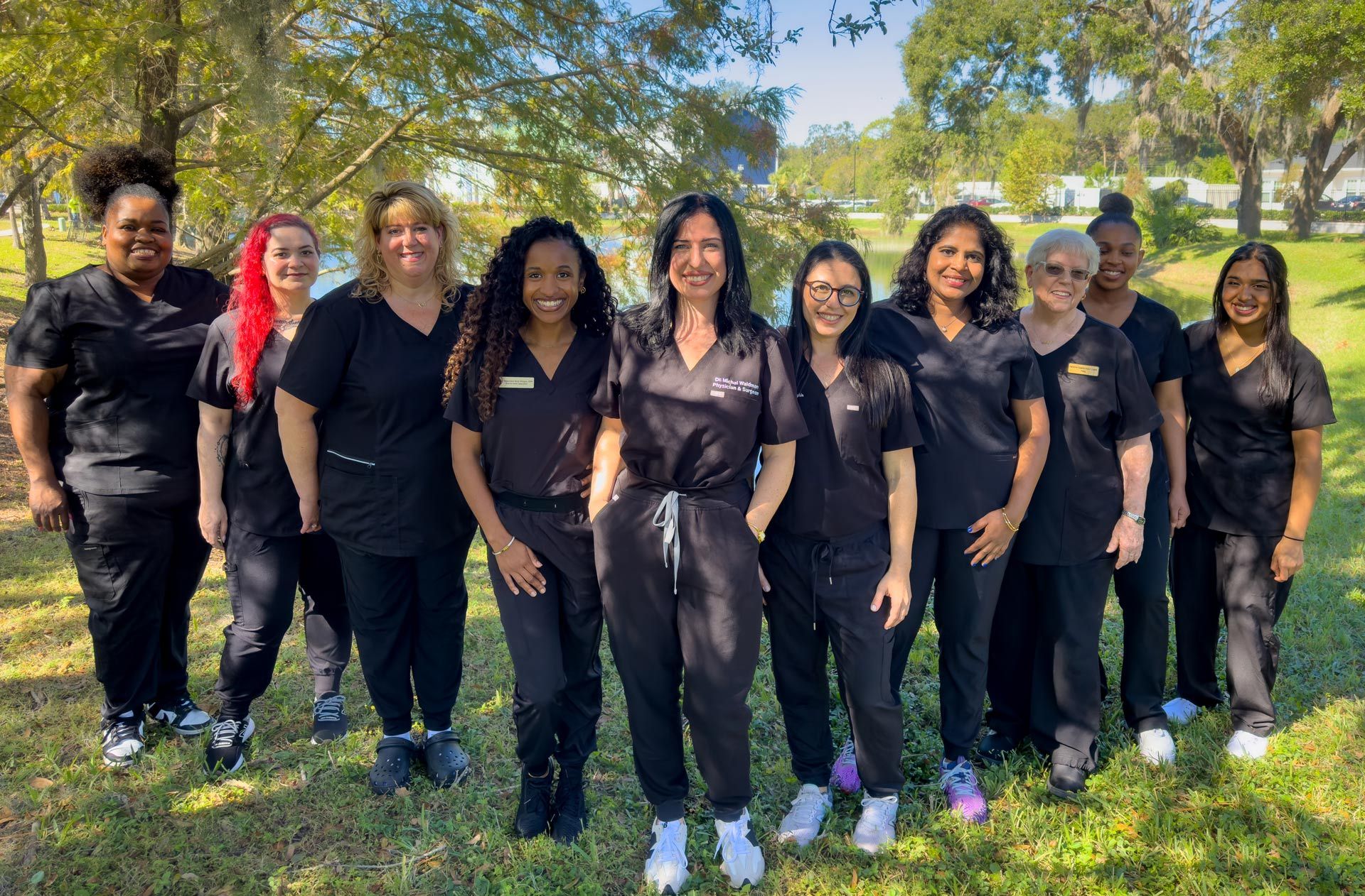 A group of women in scrubs are posing for a picture in a park.