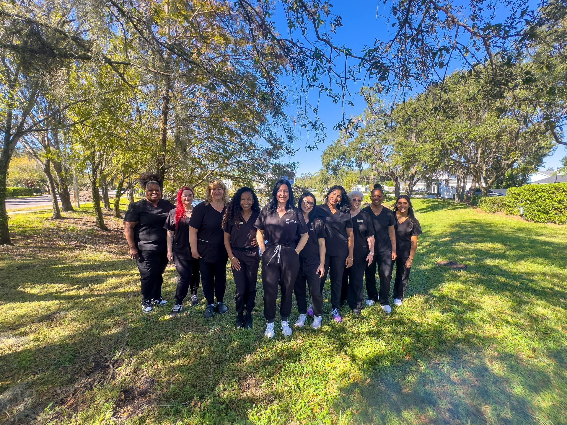 A group of nurses are posing for a picture in a park.