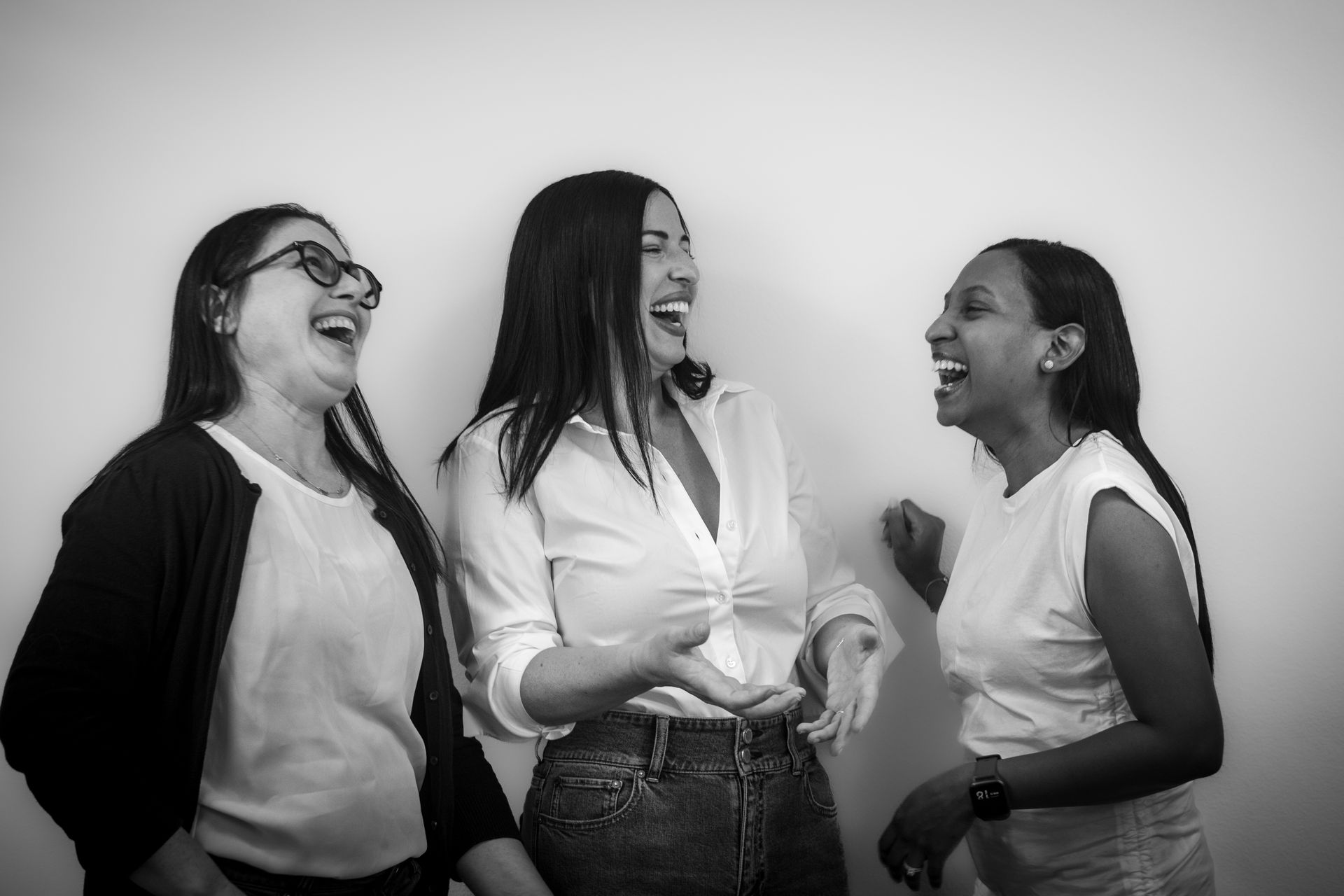 A group of women are standing next to each other and laughing in a black and white photo.