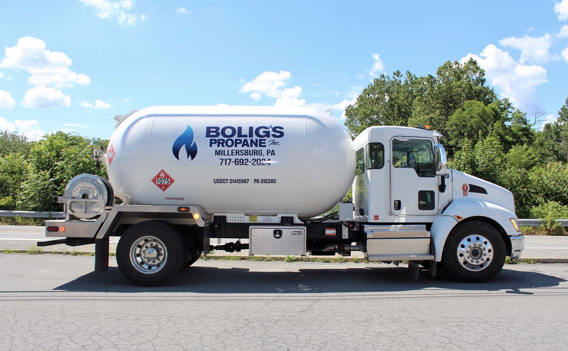 A white propane truck is parked on the side of the road.