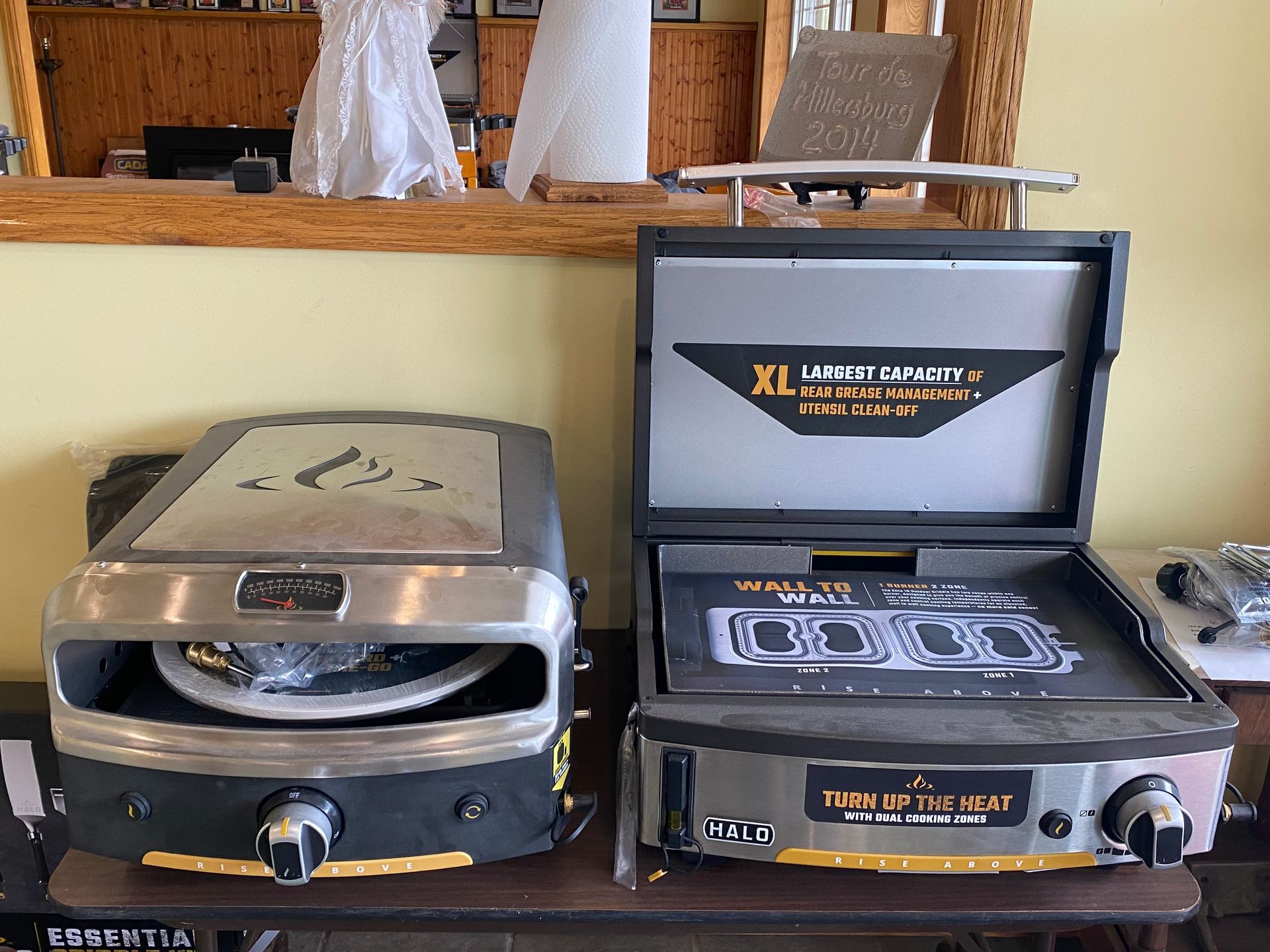 Two pizza ovens are sitting on a table in a kitchen.