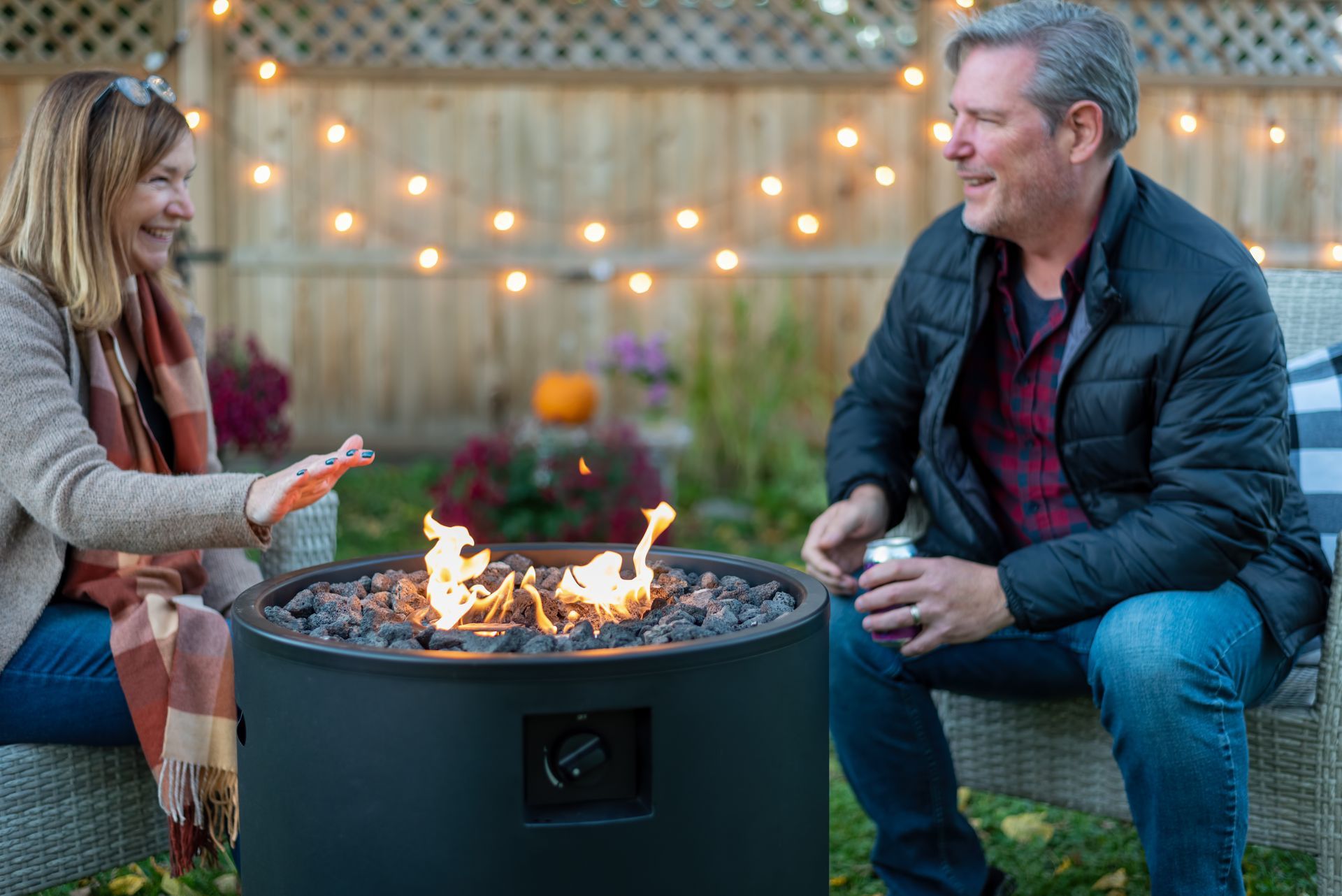 A man and a woman are sitting around a fire pit.