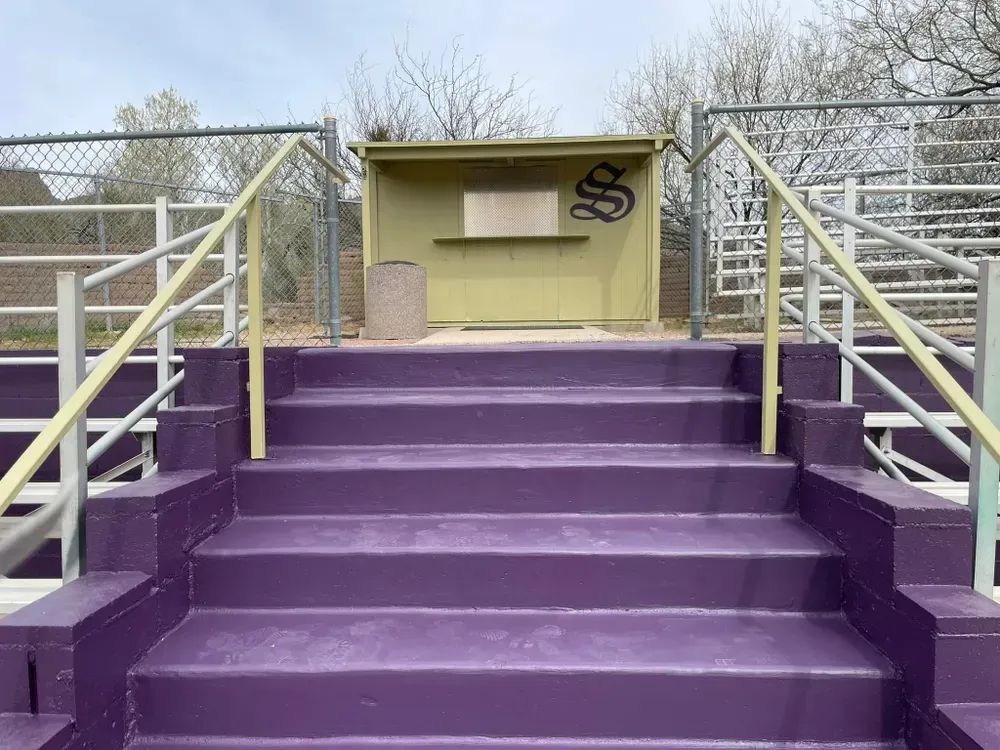 Purple stadium stairs lead to a small concession stand with a large 