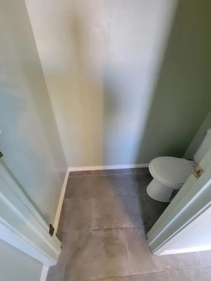 Small bathroom with gray tile floor, white toilet, and green walls.