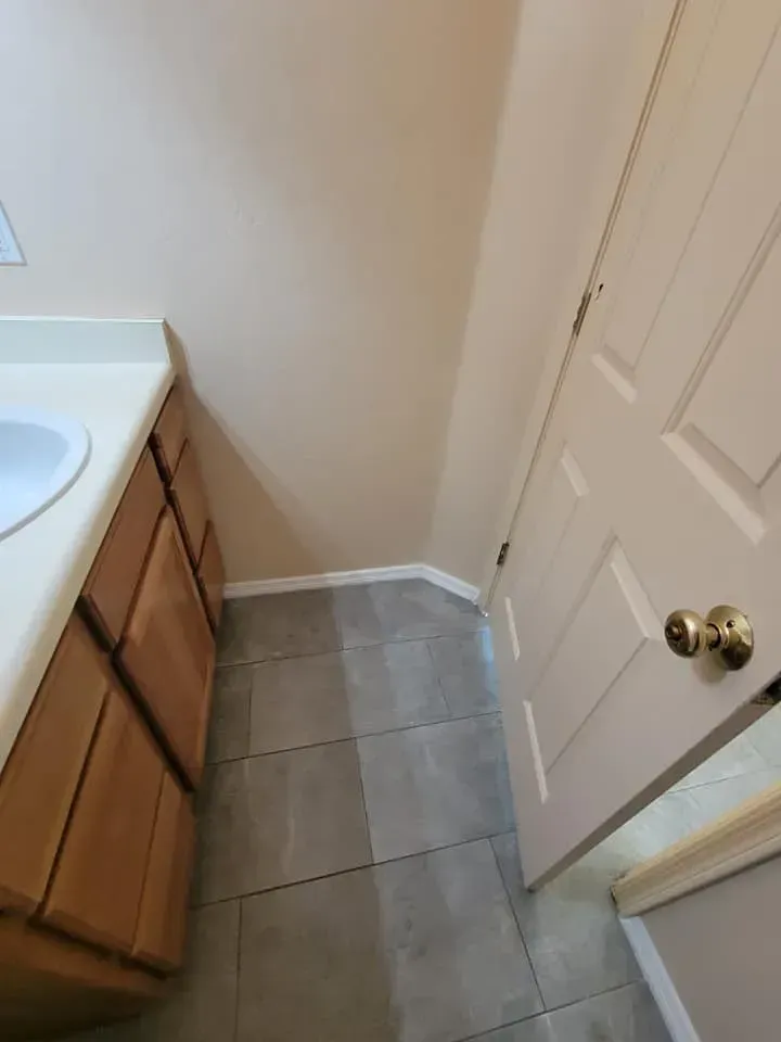 Bathroom interior with vanity, door, and tiled floor; neutral color scheme.