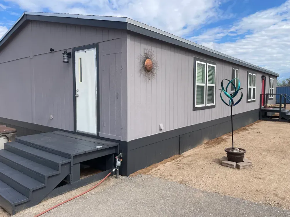Gray and white modular building with steps and a sun decoration on the wall.
