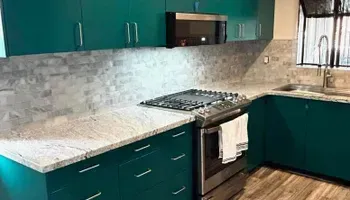 Teal kitchen with granite countertops, stainless steel appliances, and matching cabinets.