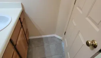 Bathroom interior with vanity, door, and tiled floor. Beige and brown tones.