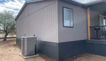 Exterior of a house with gray siding, dark trim, an AC unit, and a window.