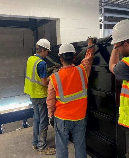 elevator technicians in safety gear inspecting cab installation