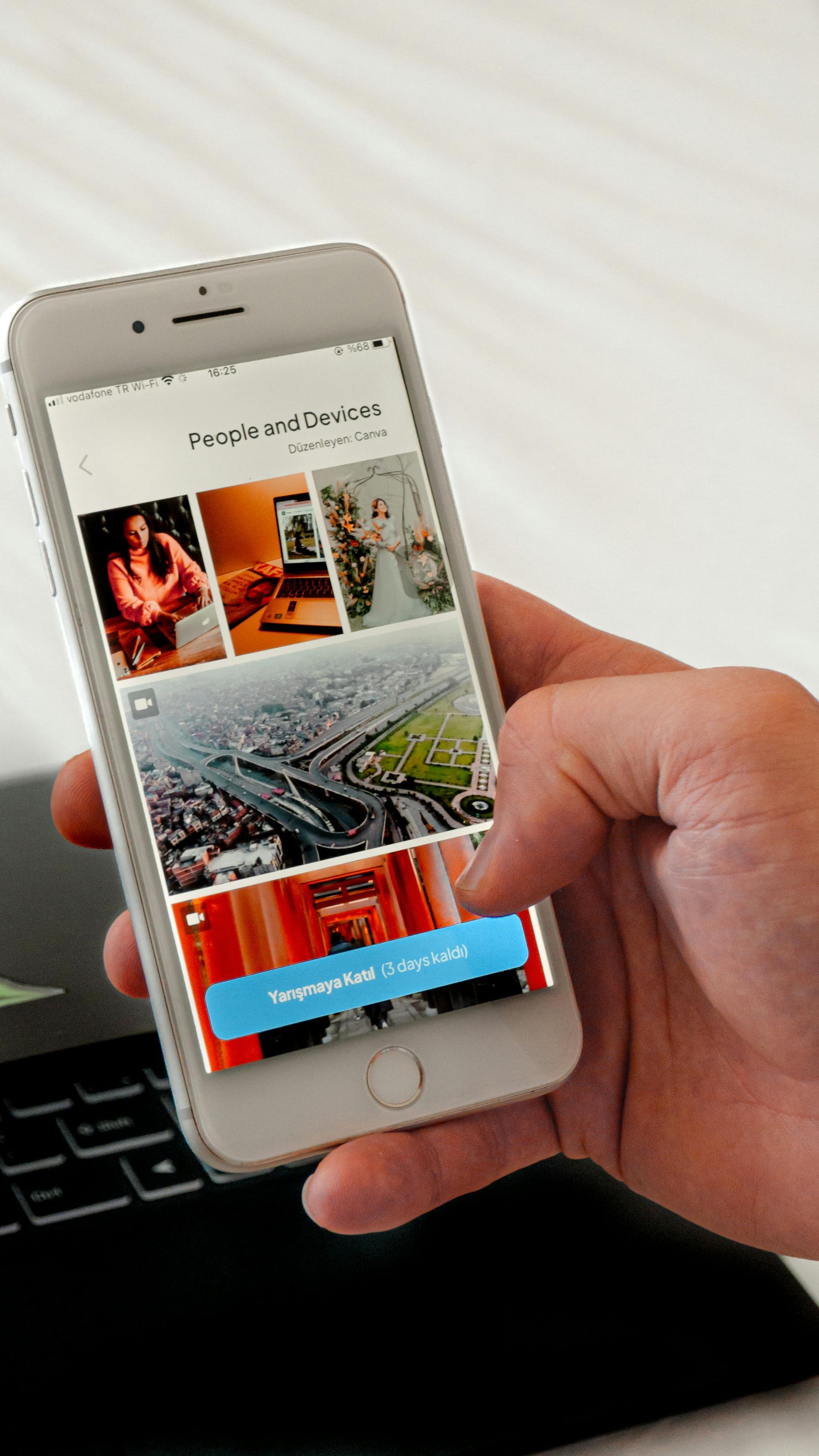 Person's hand holding a smartphone displaying a social media interface with photos and a button.