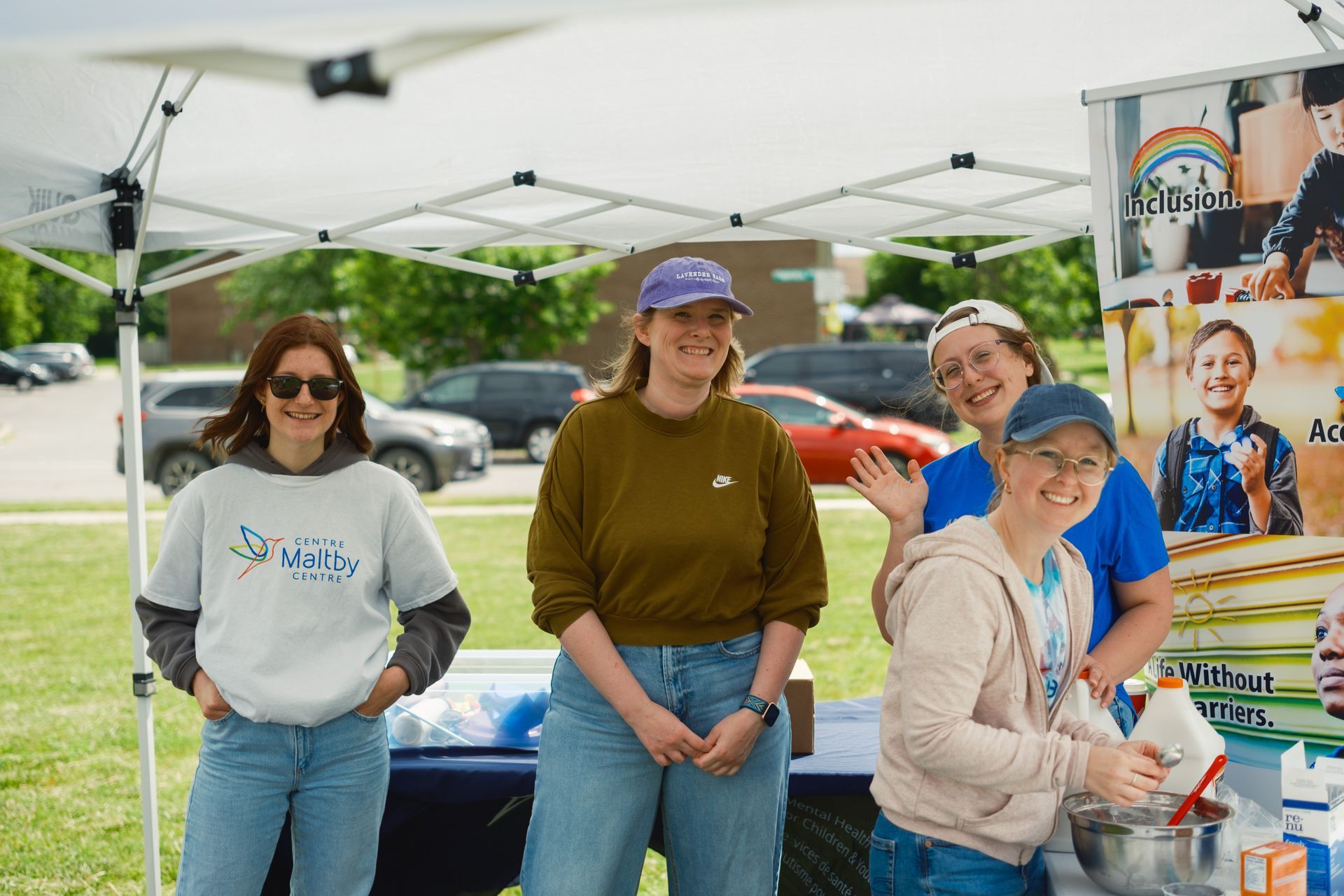 A group of women are standing under a tent in a park.