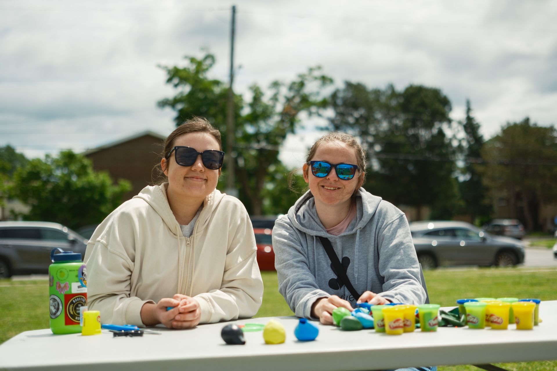 Two women are sitting at a table with play dough.