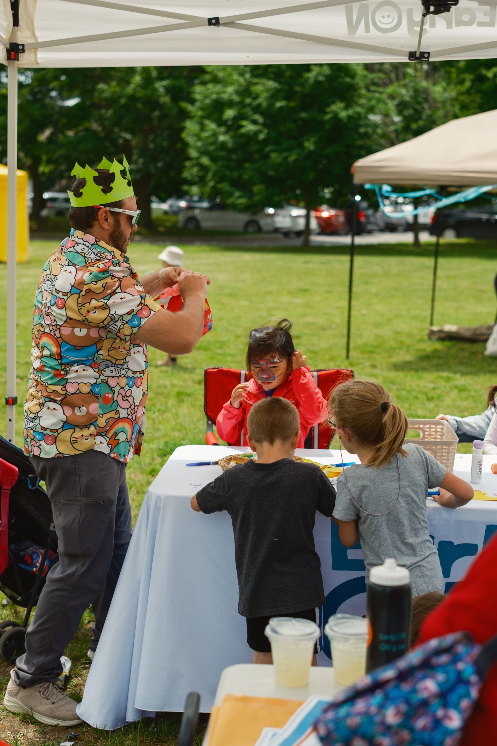 A man wearing a crown is standing next to a table with children.