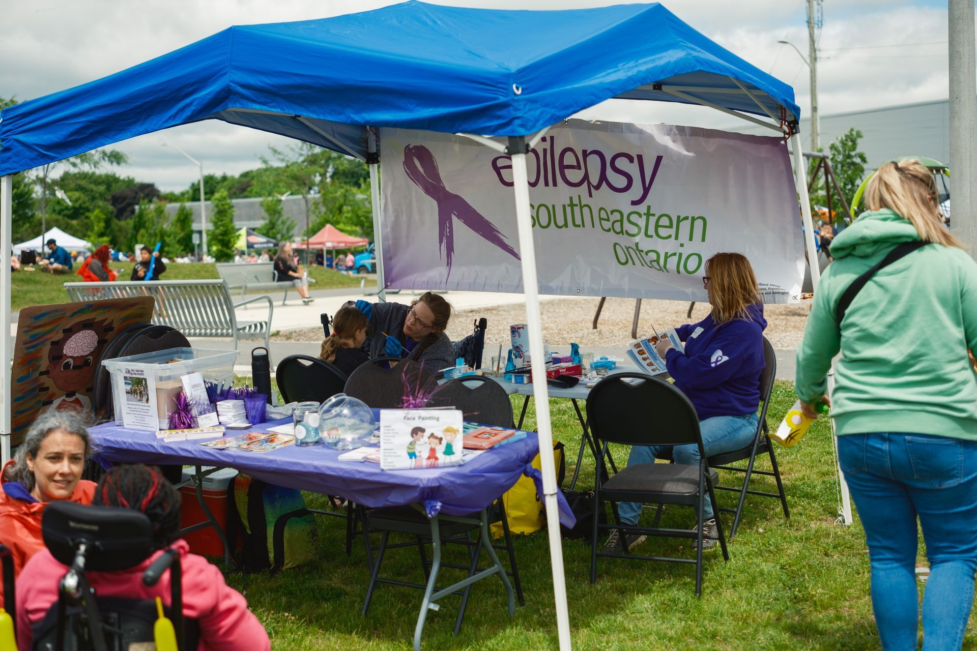 A group of people are sitting at a table under a blue tent.