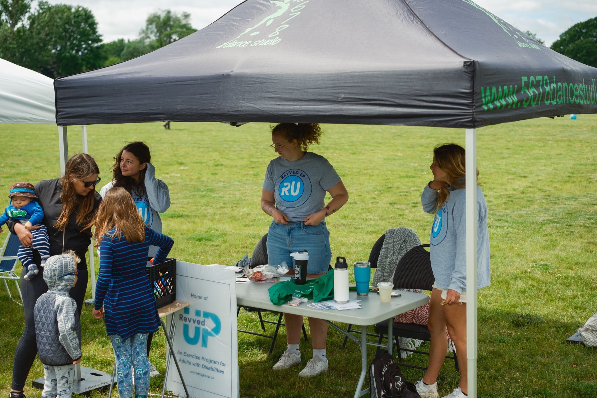 A group of people are standing under a tent in a field.