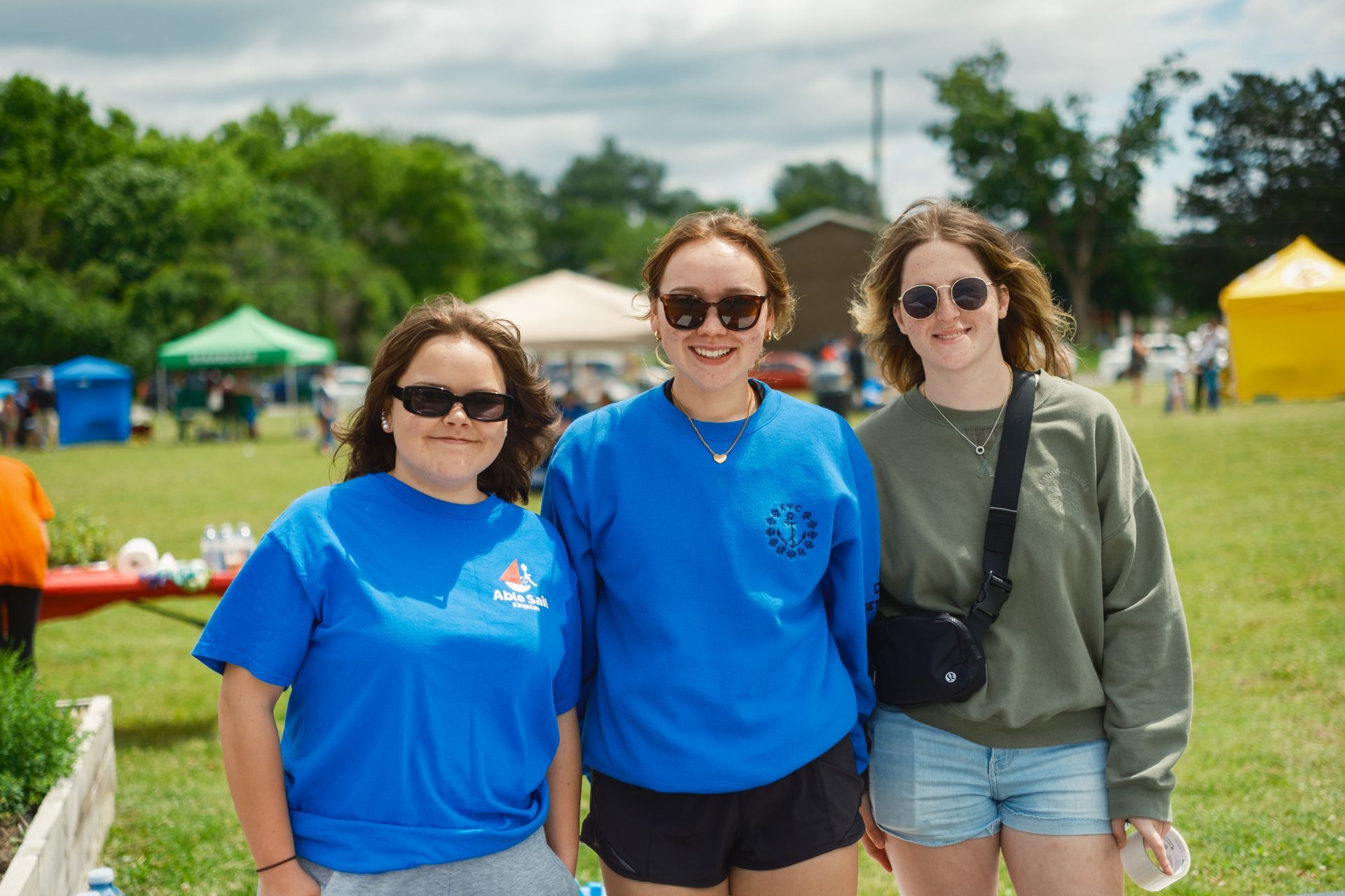 Three young women are posing for a picture in a field.