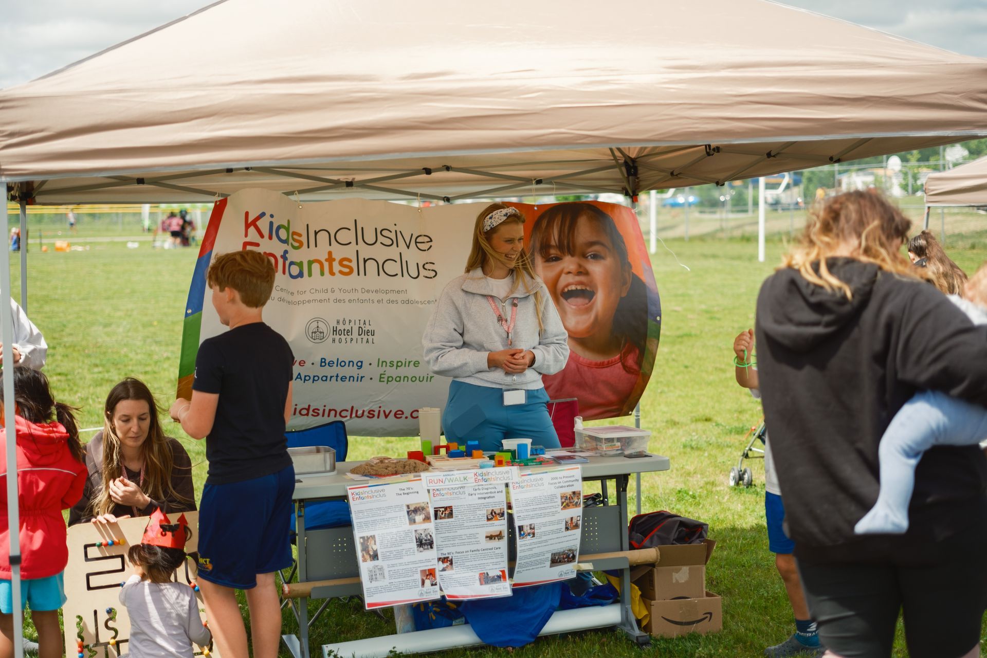 A group of people are standing under a tent in a field.