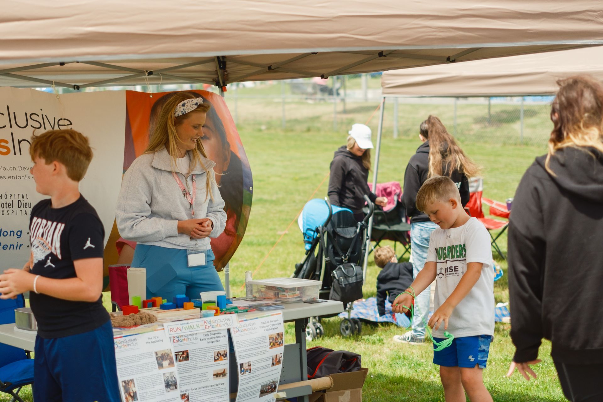 A group of people are standing around a table under a tent.