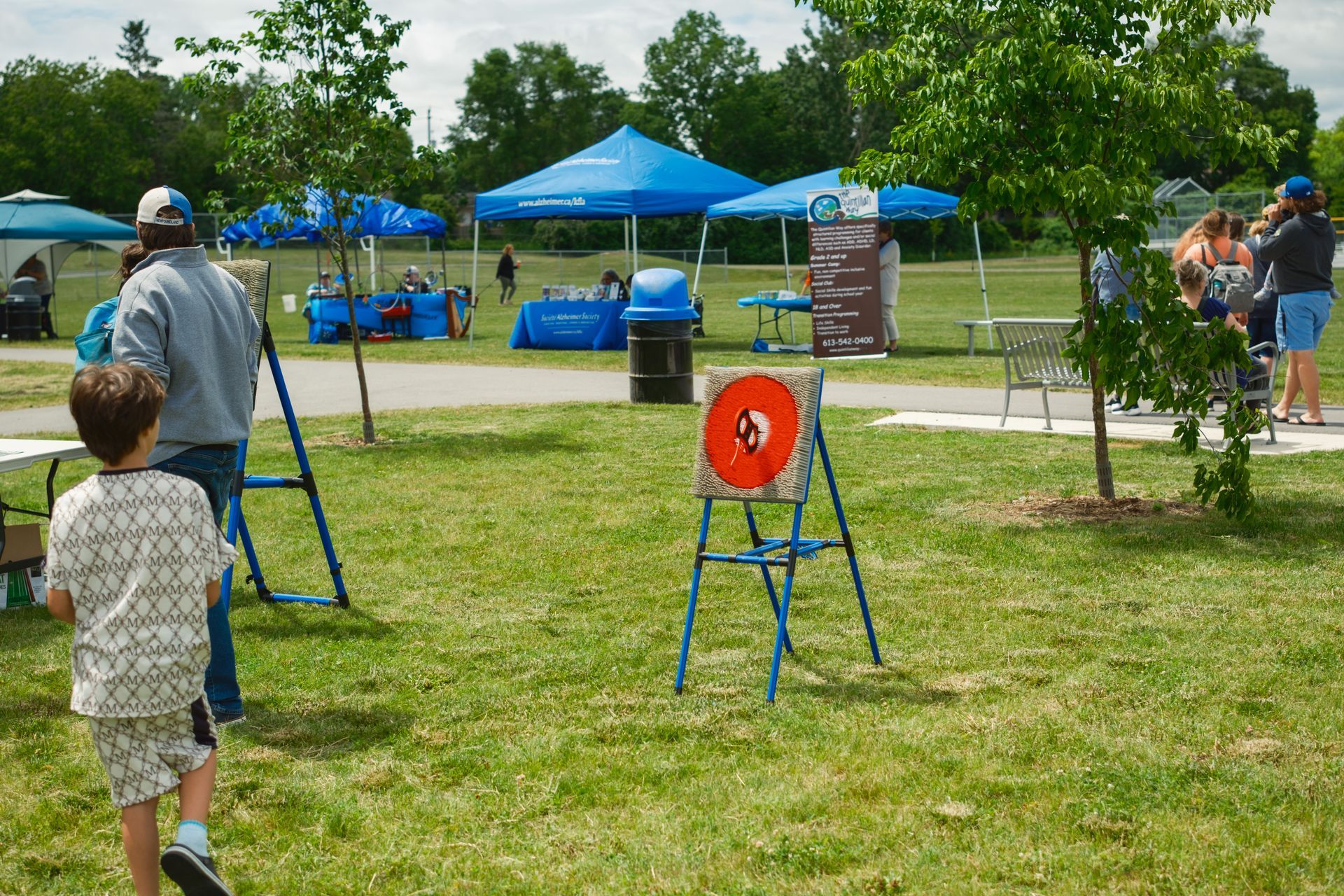 A little boy is running towards a frisbee target in a park