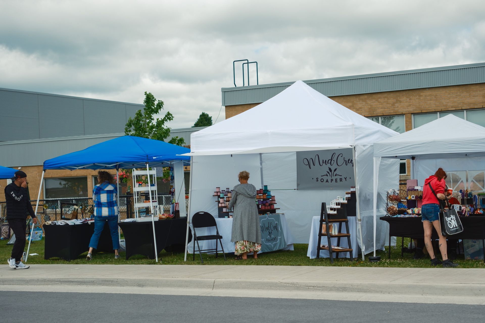 A group of people are standing in front of a row of tents.