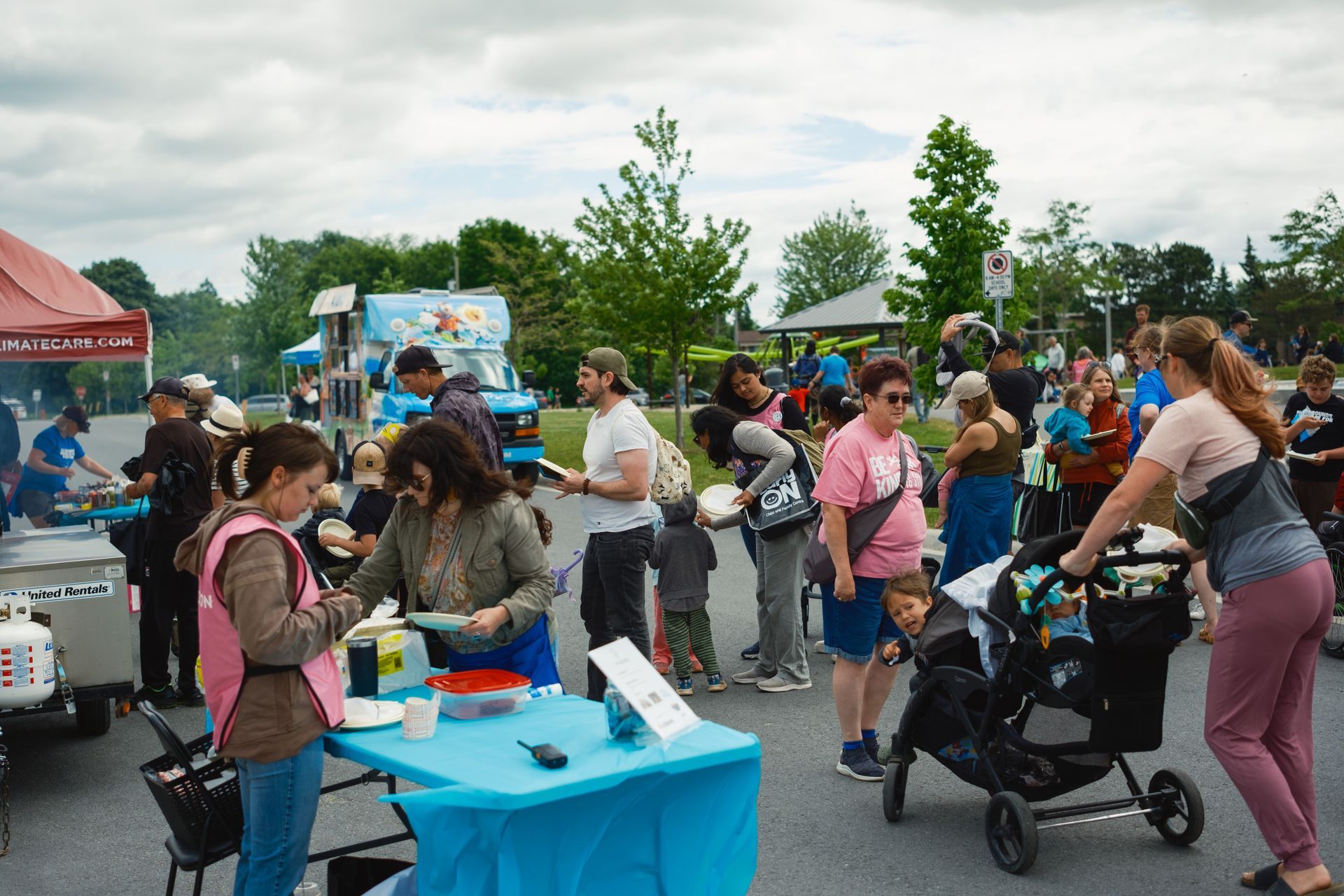 A group of people are standing around a table in a parking lot.