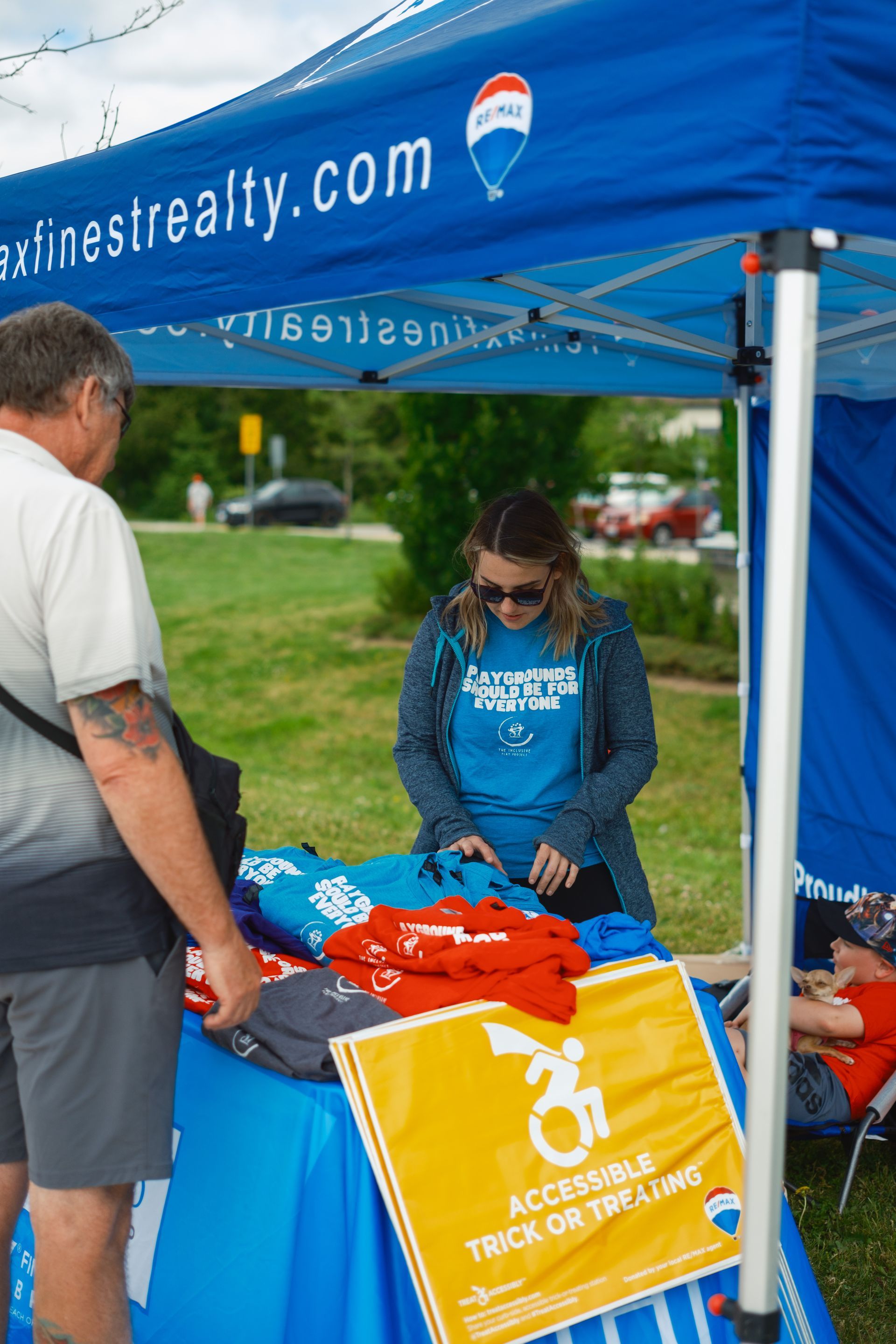 A man and woman are standing in front of a table under a blue tent.