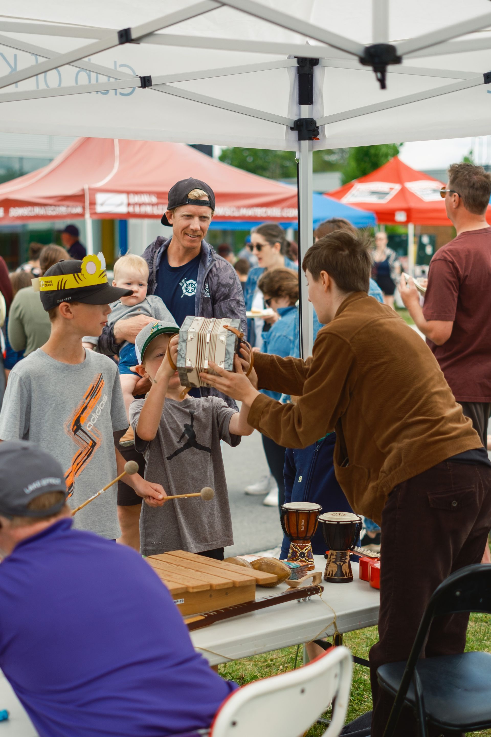 A group of people are standing around a table under a tent.