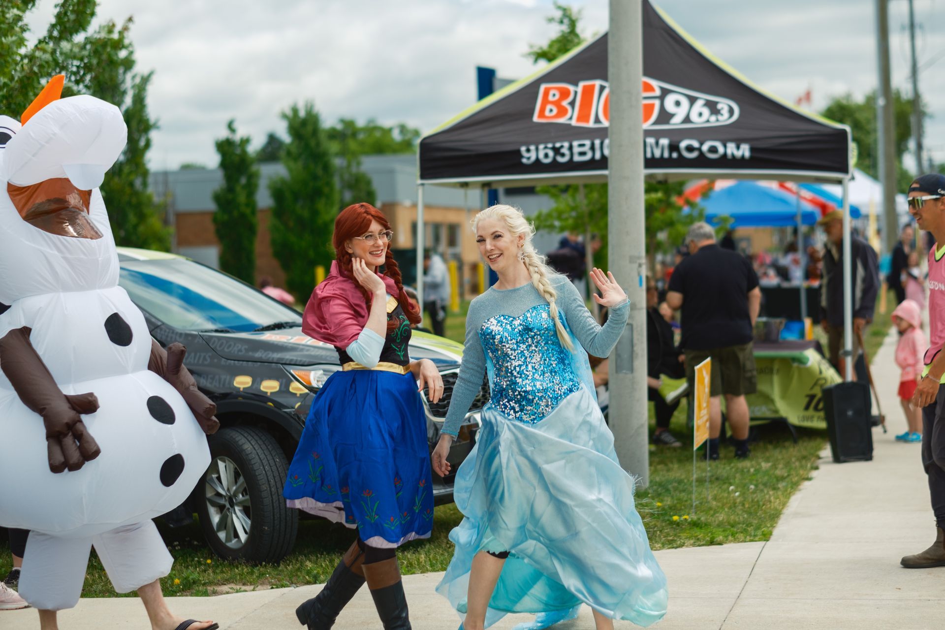 A group of people dressed as frozen characters are walking down a sidewalk.