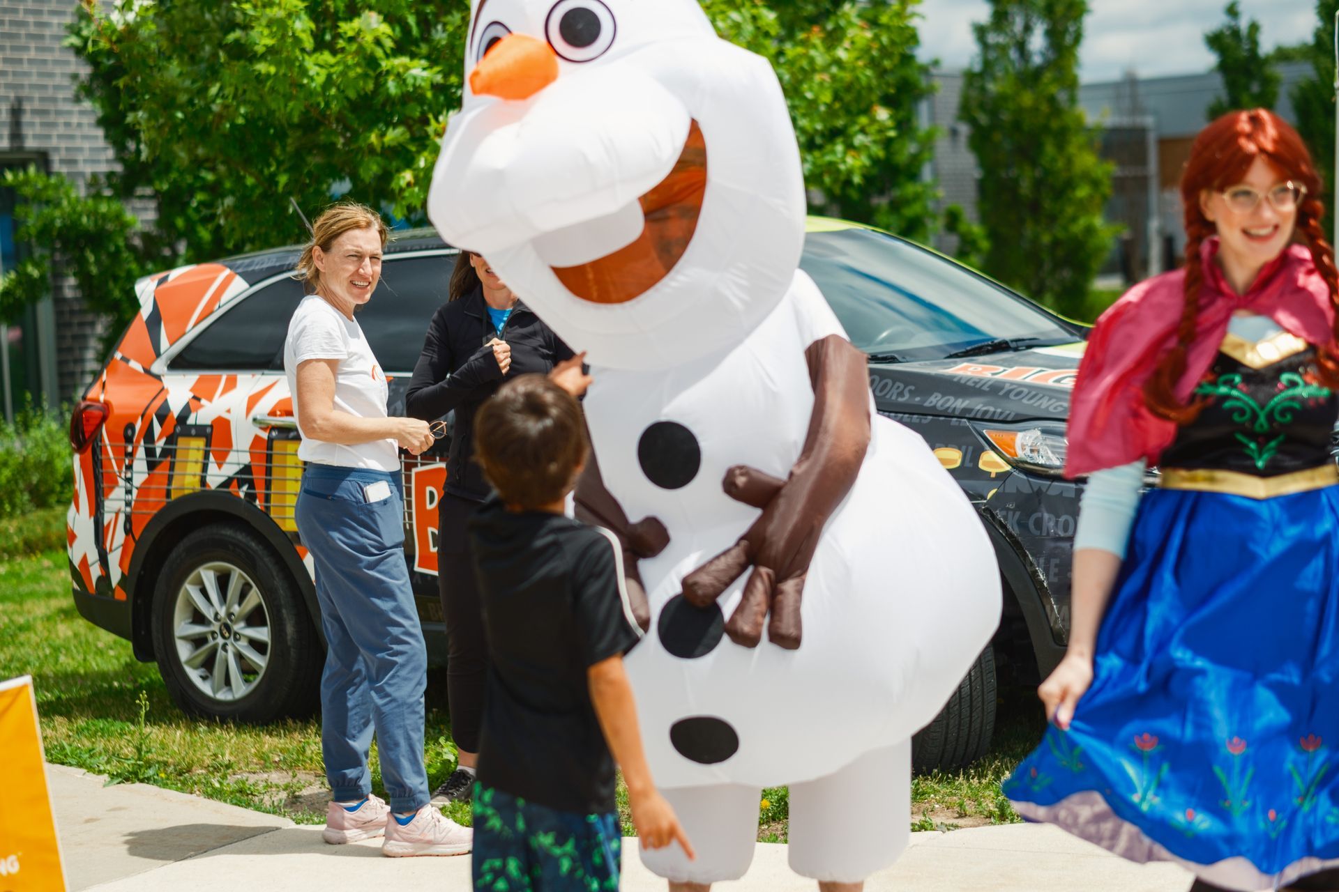 A group of people are standing around a snowman costume.