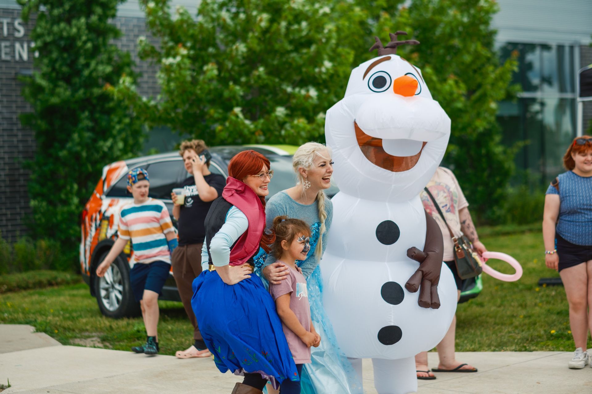 A group of people are standing around a snowman costume.