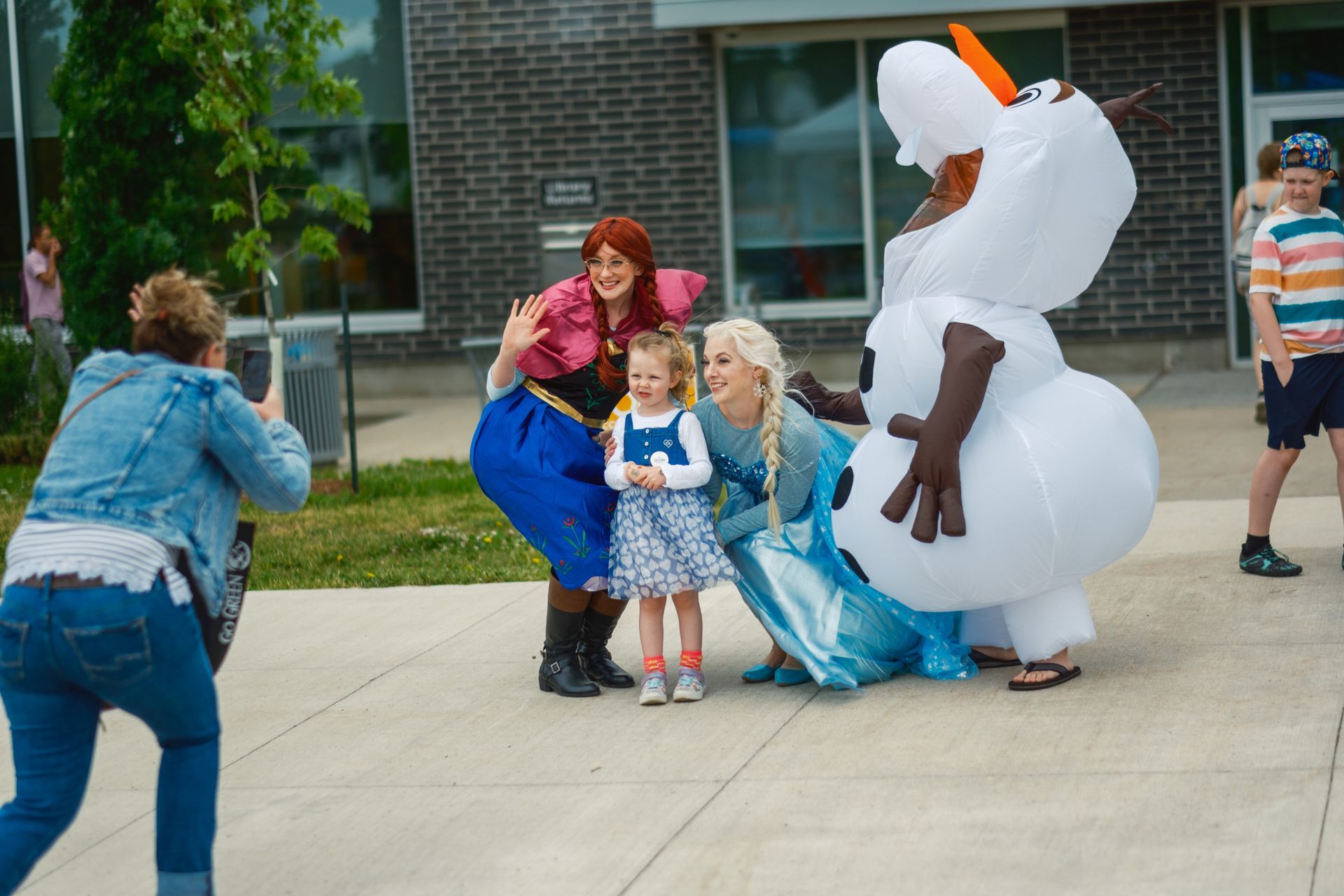 A woman is taking a picture of anna and elsa and a snowman