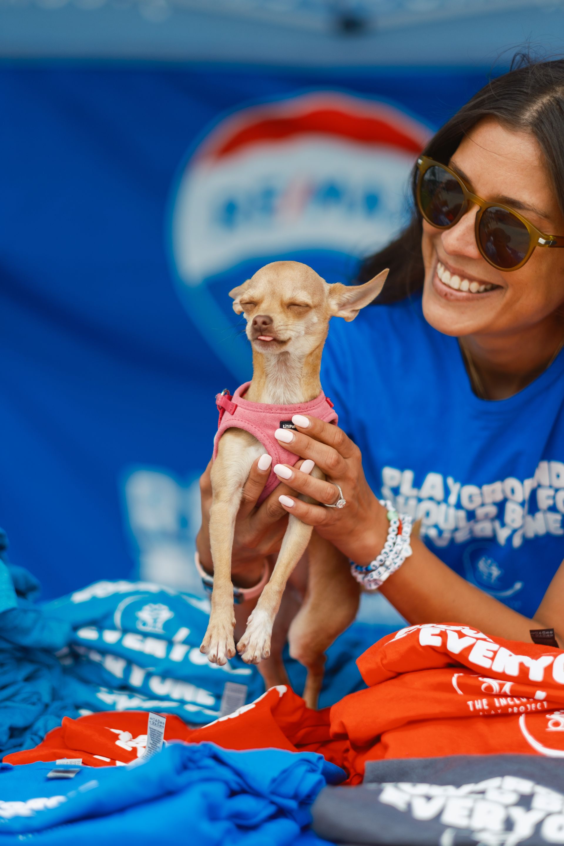 A woman in a blue shirt is holding a small dog