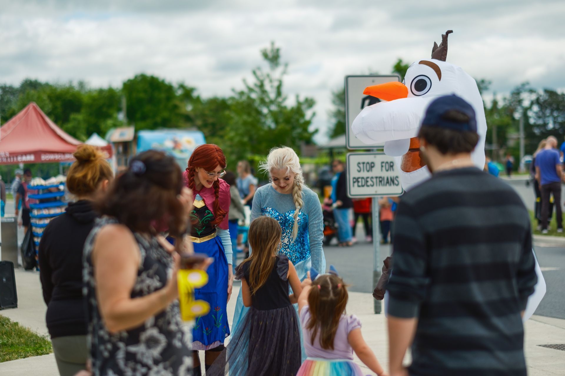 A group of people are walking down a street with a frozen mascot.
