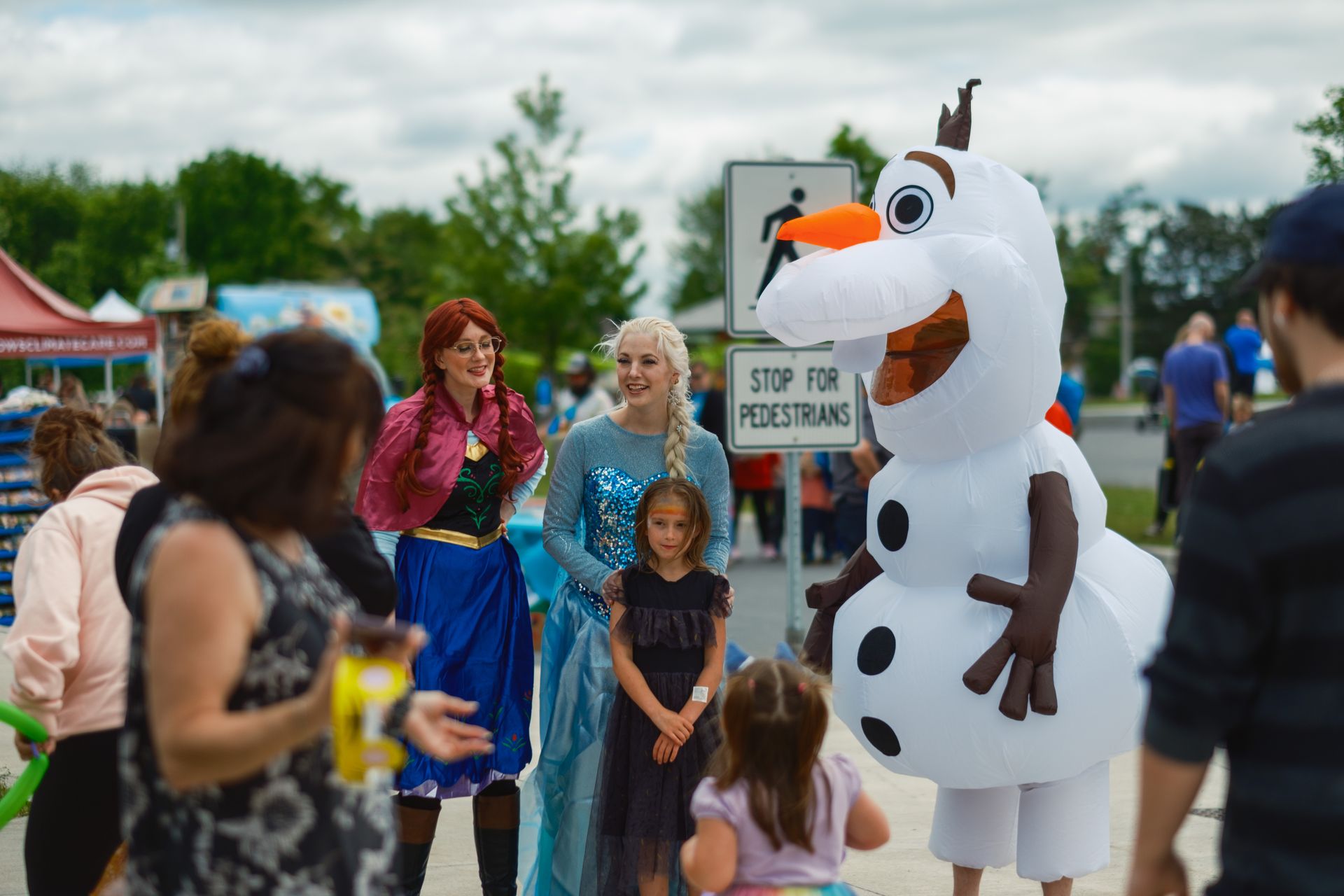 A group of people are standing around a snowman dressed as olaf from frozen.