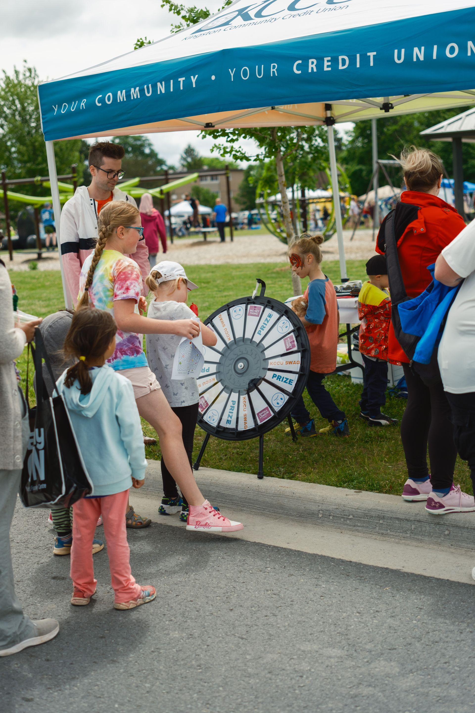 A group of children are playing a wheel of fortune game under a tent.